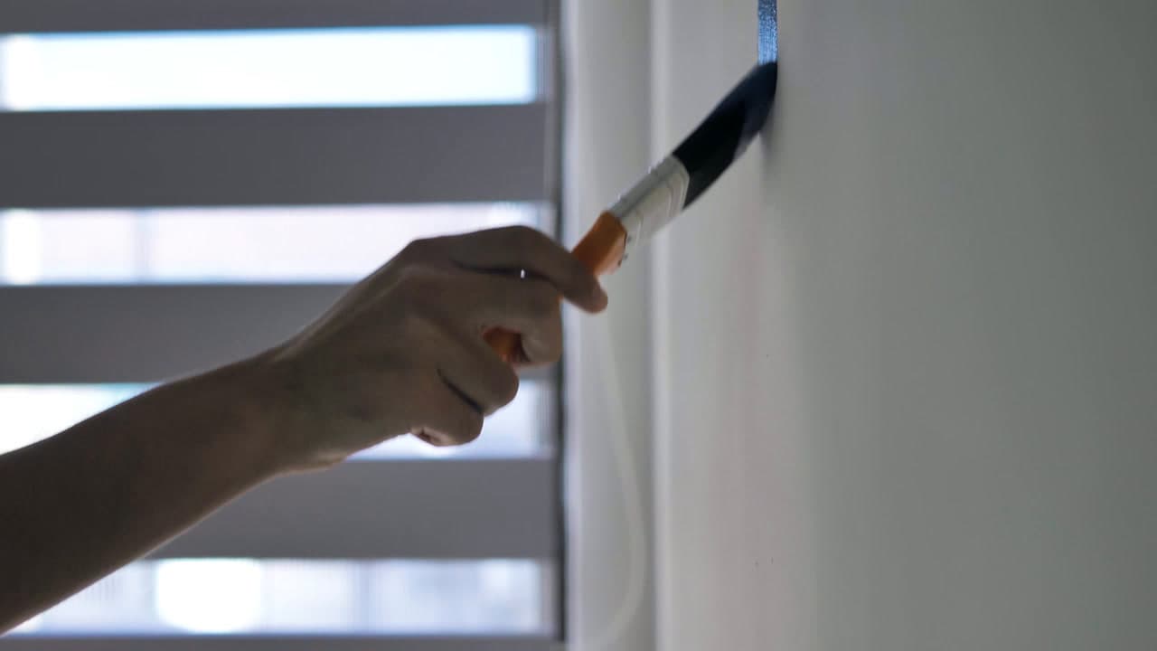 Kwast brengt verf aan op een kozijn tijdens schilder- en onderhoudswerk